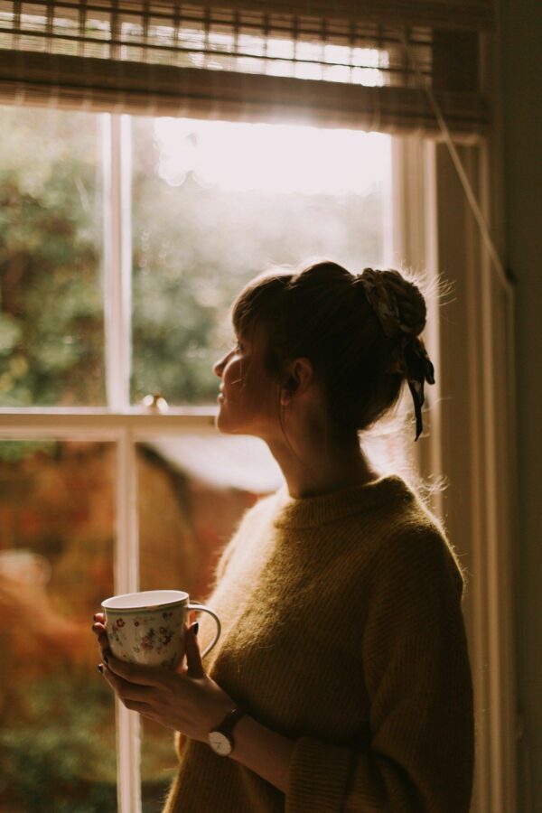 Woman holding a cup of tea by a window