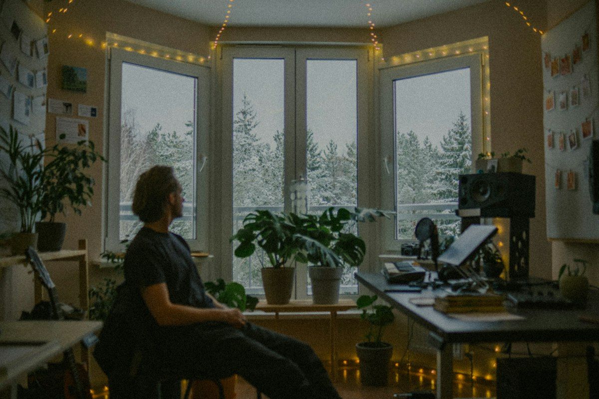 Man looking out a window in a cozy room